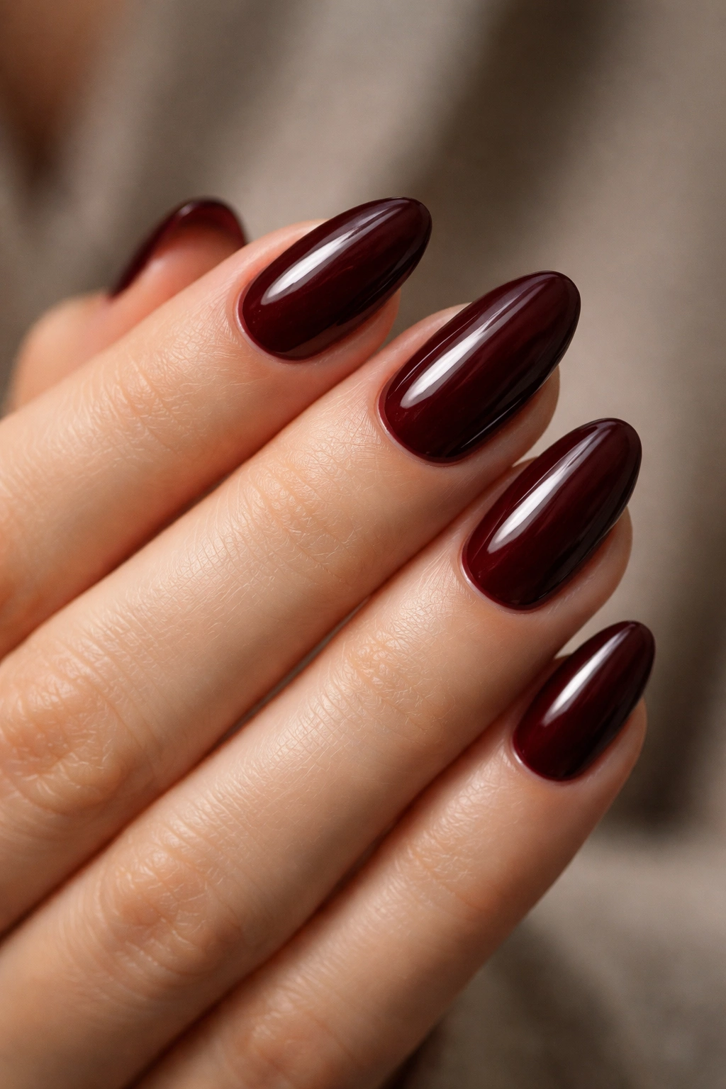 Close-up of oxblood short almond nails with glossy finish