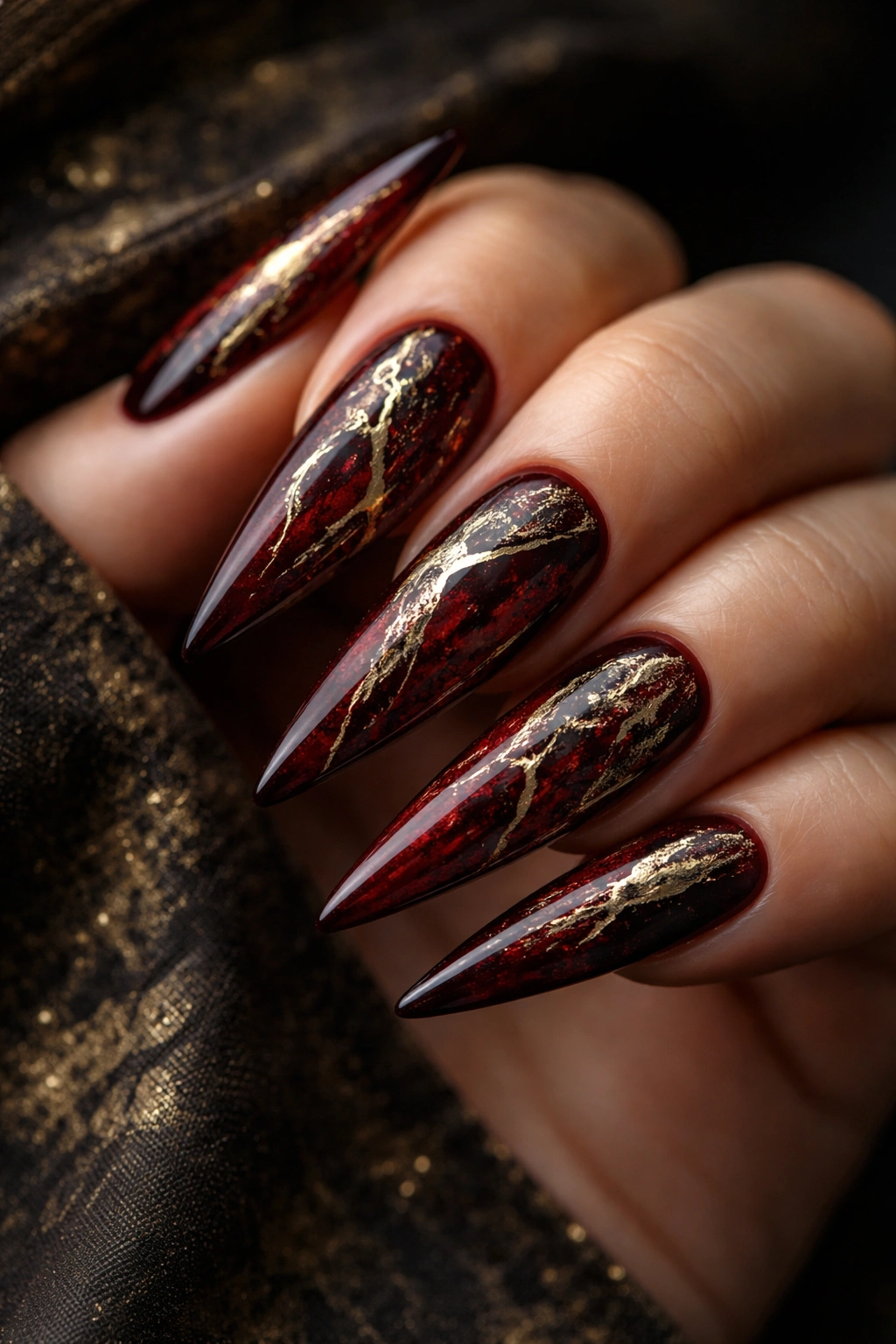 Oxblood stiletto nails with weathered gold accents.