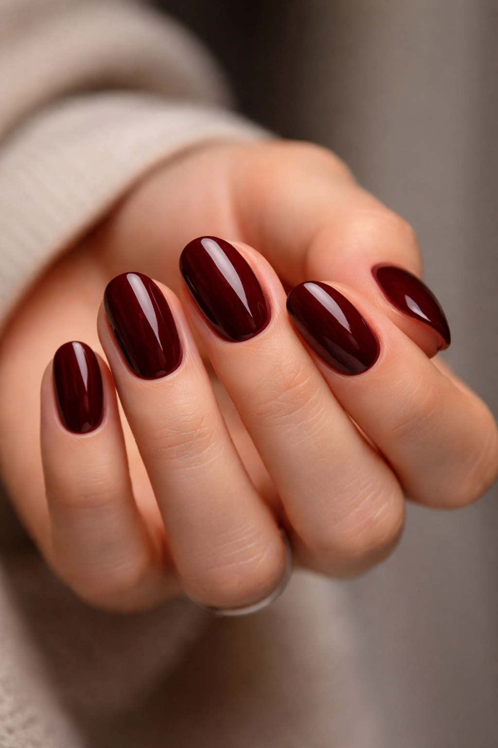 Close-up of oxblood short oval nails on hand