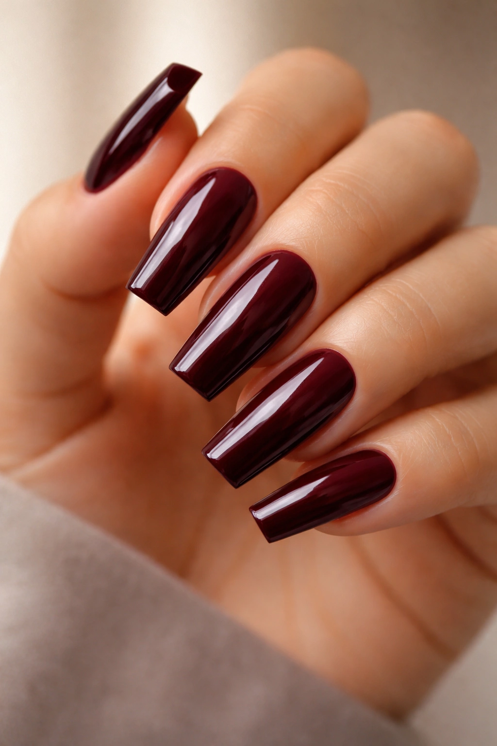 Close-up of oxblood nails with a sharp square tip and glossy finish.
