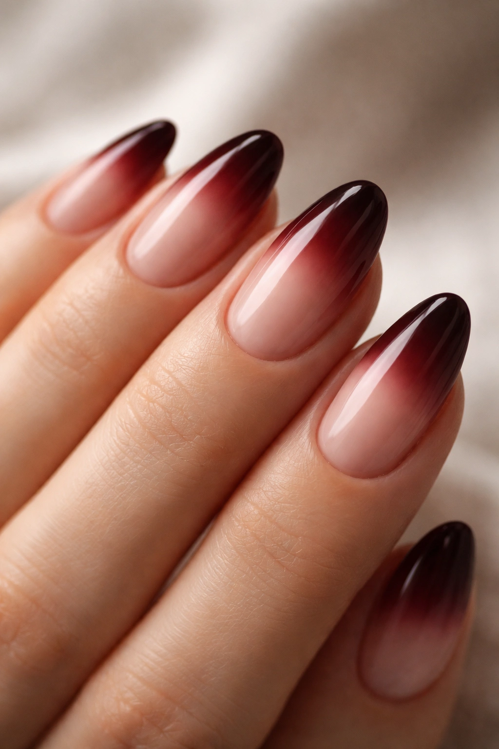 Close-up of short almond nails with oxblood ombre French gradient