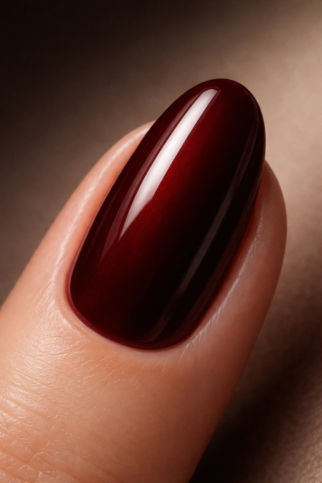Close-up of oxblood red nail with warm brown undertones and glossy finish