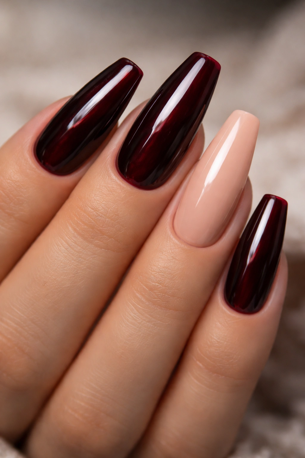 Nails with oxblood red color and a nude accent nail