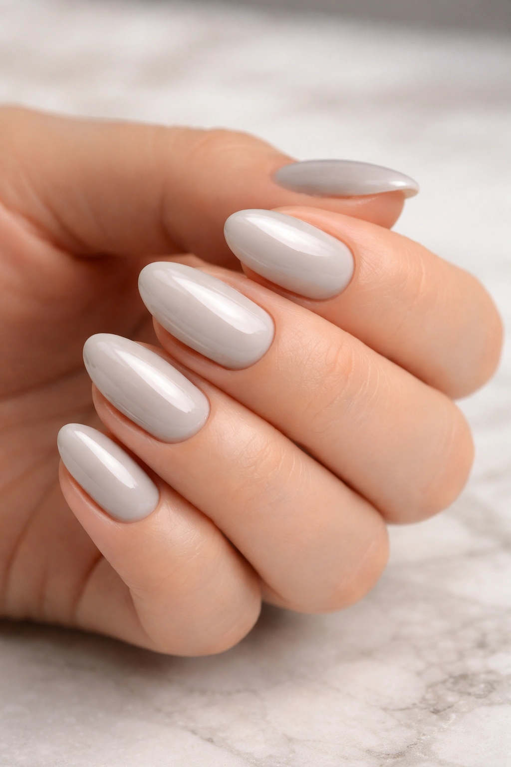 Close-up of short oyster gray almond nails with a pearl undertone and glossy finish.
