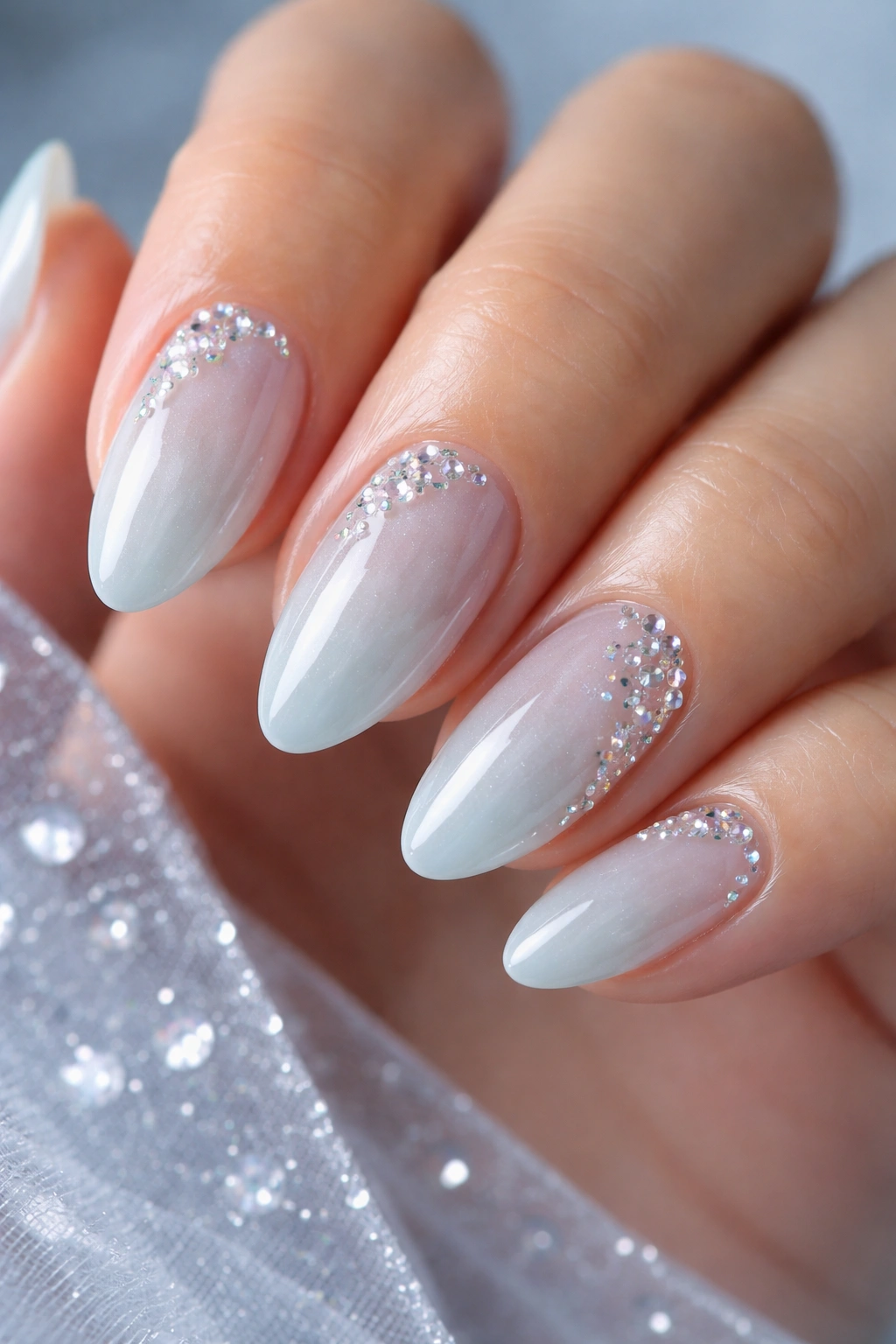 Close-up of pale blue almond nails with ice-effect stones