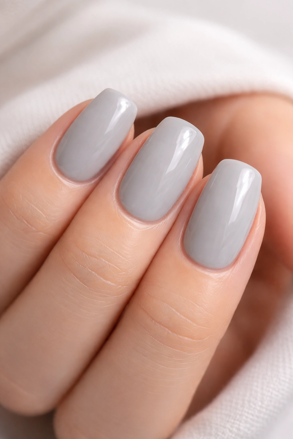 Close-up of pale gray nails with a clear high-gloss topcoat
