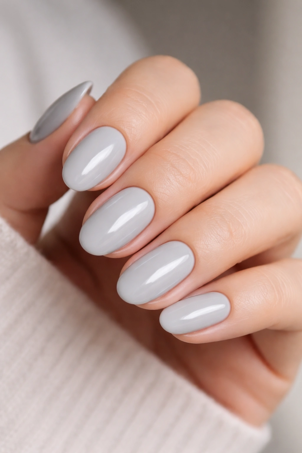 Close-up of pale gray short oval nails with a glossy finish.