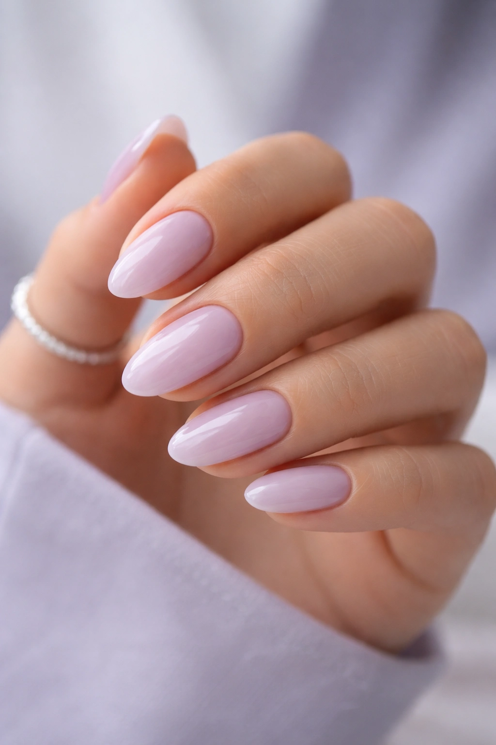 Close-up of pale lavender sheer nails on short almond nails with soft pastel appearance
