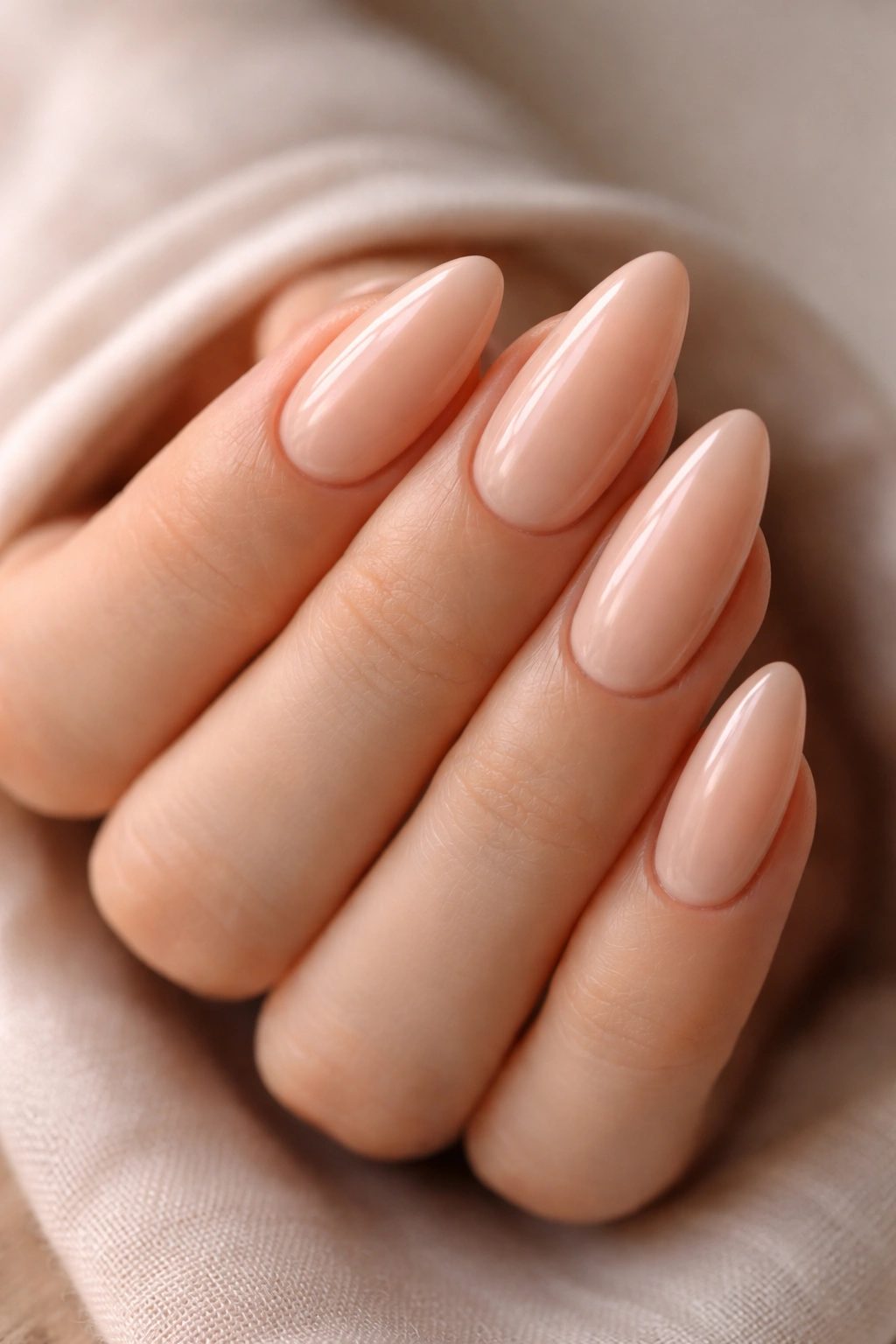 Almond nails in pale peach with warm glow and glossy finish