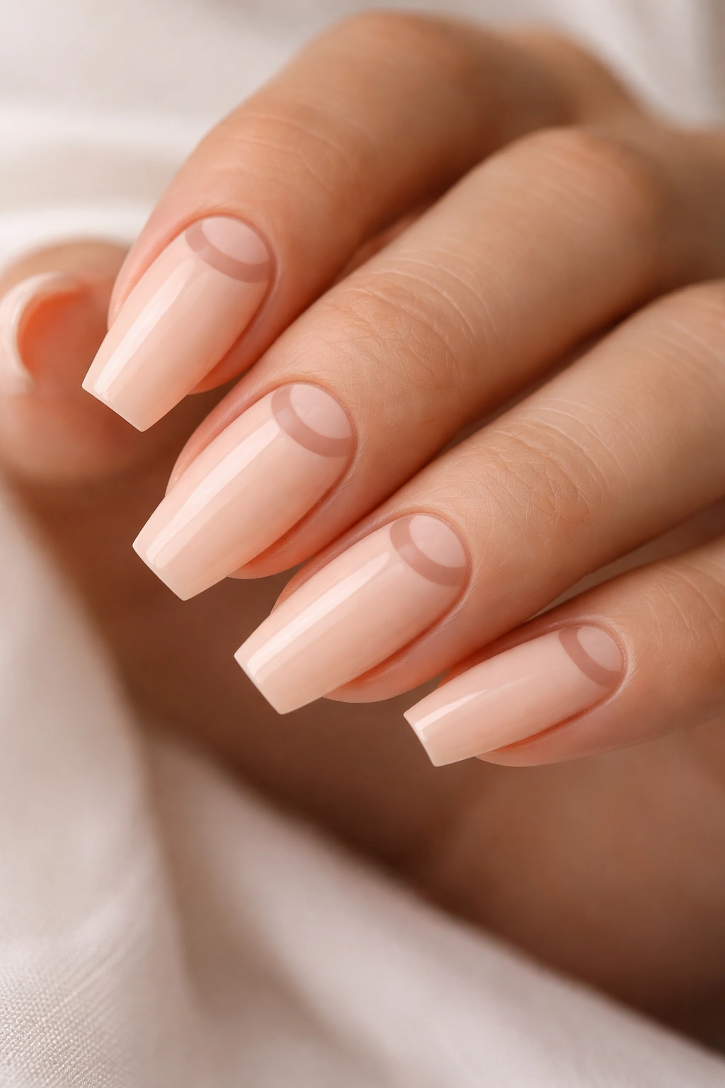 Close-up of pale peach coffin nails with a negative-space half-moon at the cuticle
