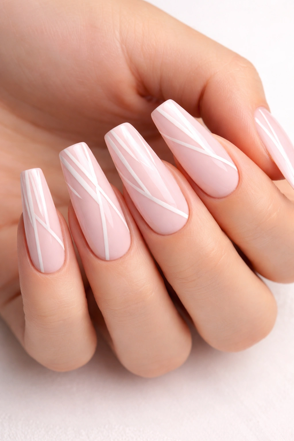 Close-up of pale pink coffin nails with geometric line work