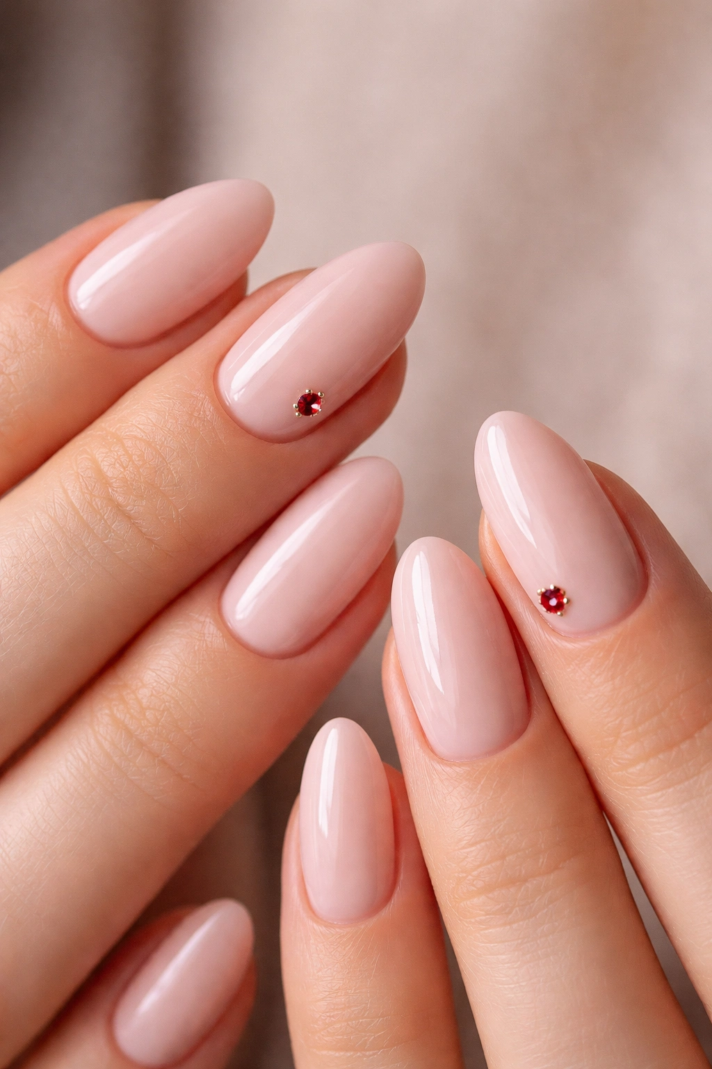 Pale pink nails with a single red gem near the cuticle