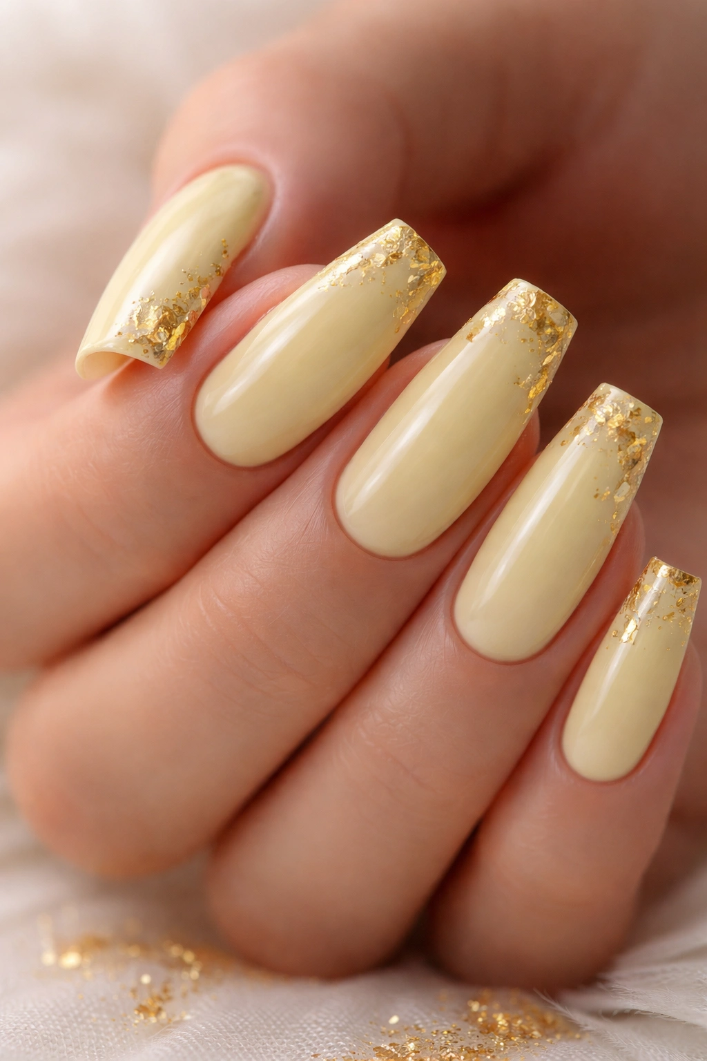 Close-up of pale yellow coffin nails with fine gold leaf details
