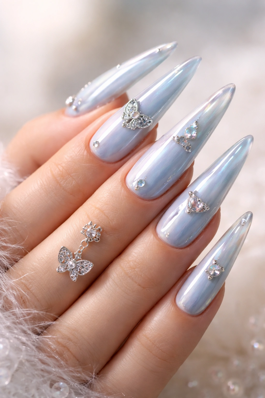 Pastel baby blue stiletto nails with small charms and chrome accents