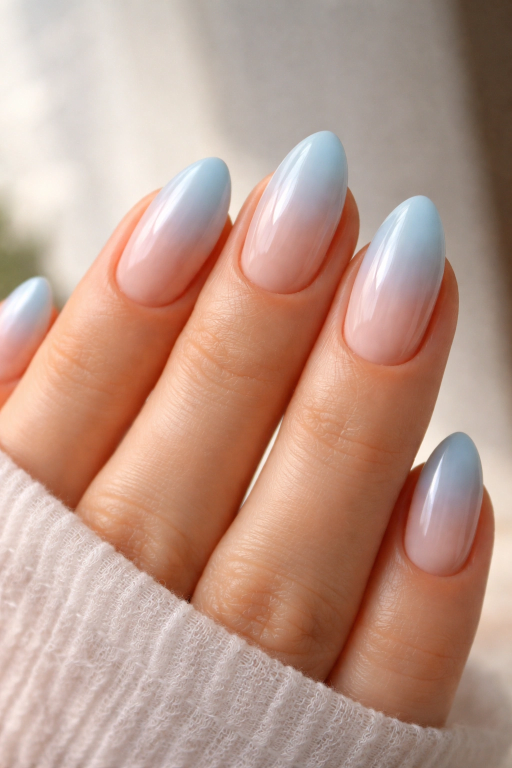 Close-up of pastel blue ombré almond nails showing a smooth gradient