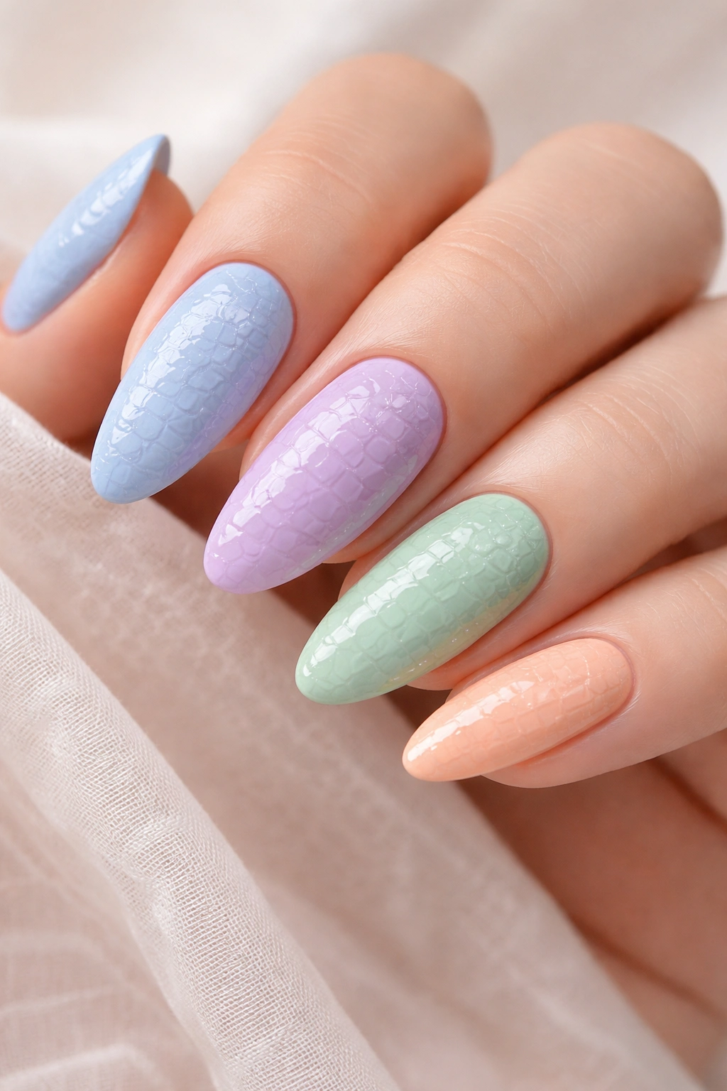 Close-up of pastel crocodile-textured nails in soft blue, lavender, mint green, peach, and pale yellow
