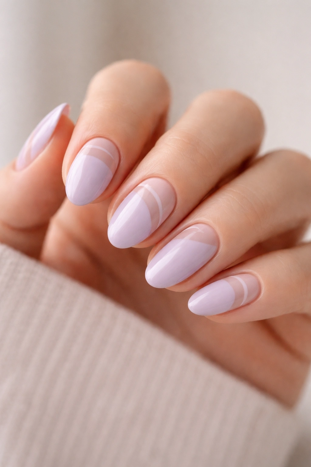 Close-up of short almond nails in pastel lilac with negative-space designs on a neutral background