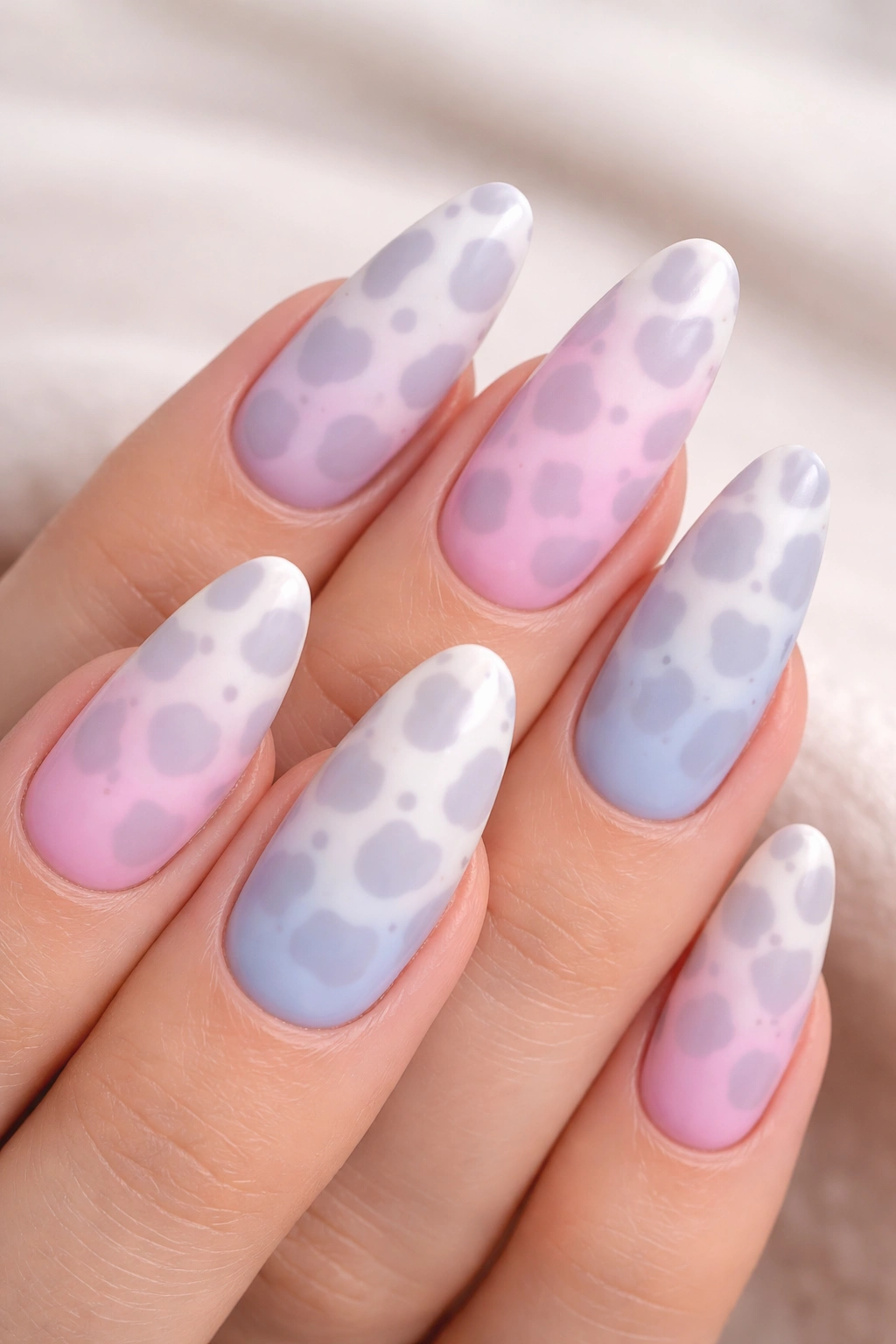 Close-up of pastel ombre cow print nails with subtle gray spots