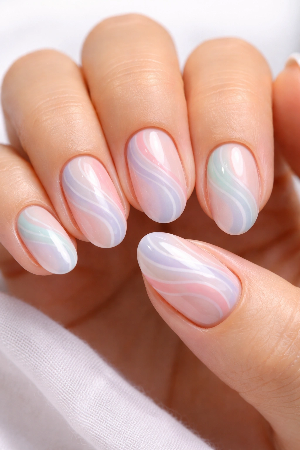 Close-up of short almond nails with pastel rainbow swirl nail art