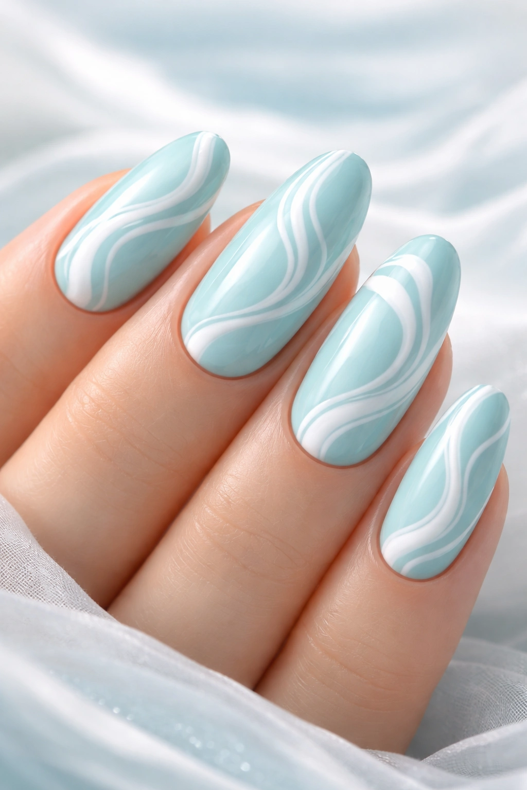 Close-up of pastel teal nails with white swirl designs