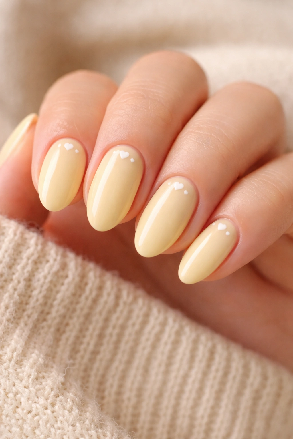 Pastel yellow nails with micro hearts on short almond nails