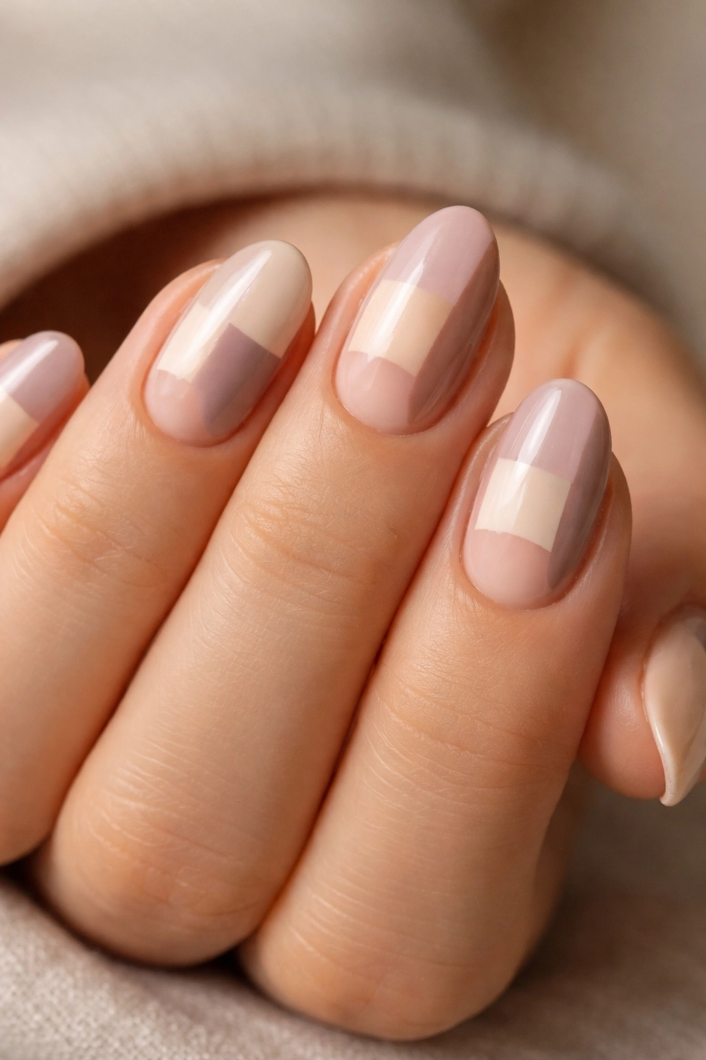 Close-up of short almond nails with half-moon patchwork in neutral tones