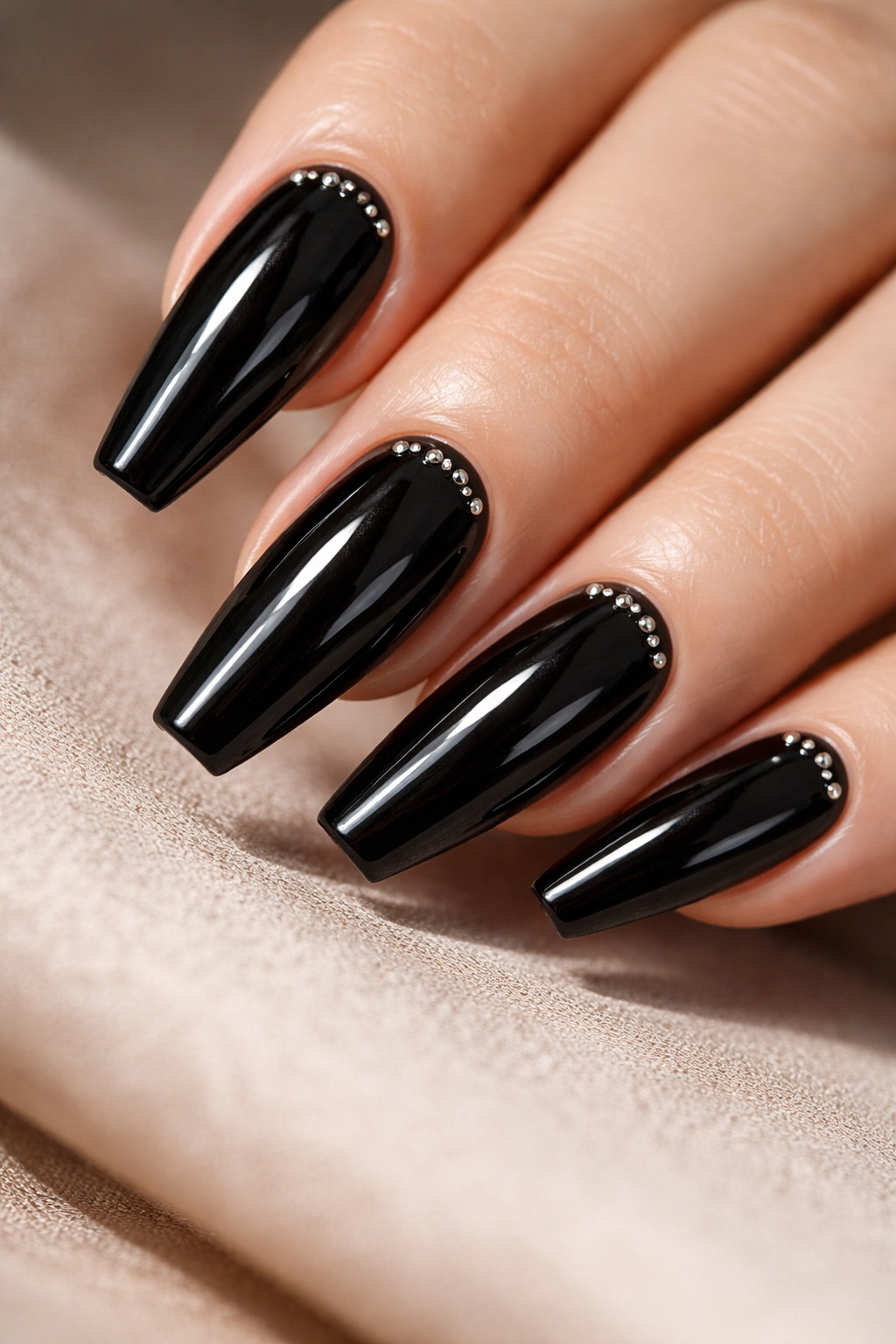 Close-up of patent black nails with tiny micro studs near the cuticle