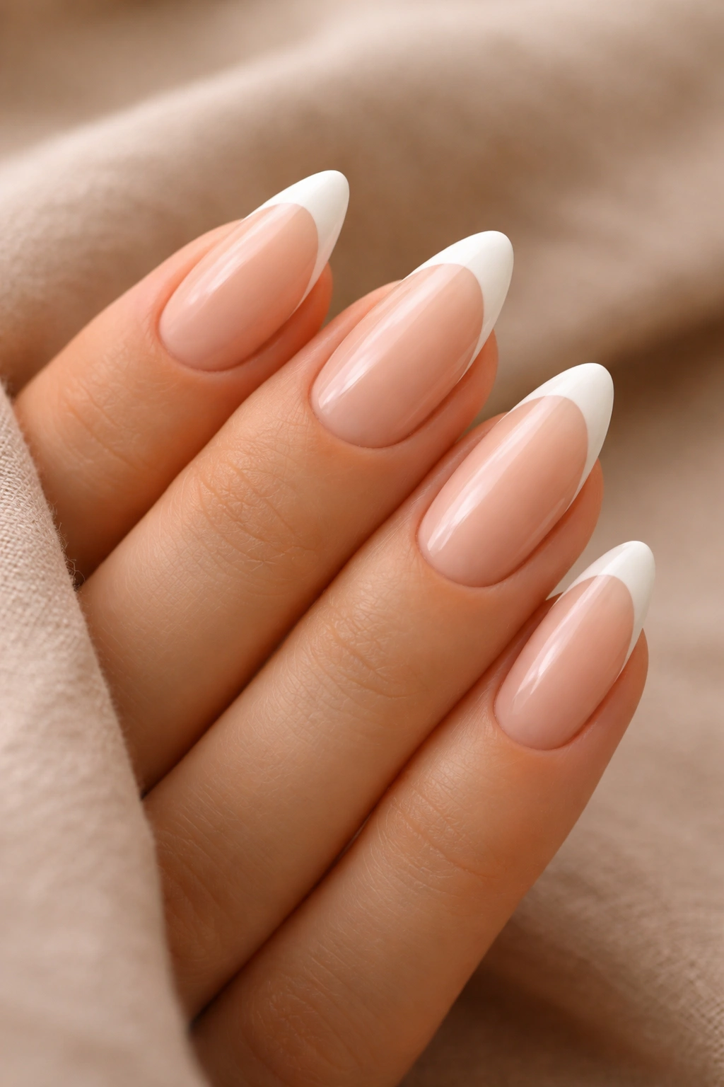 Close-up of almond nails with sheer peach base and cream tip.