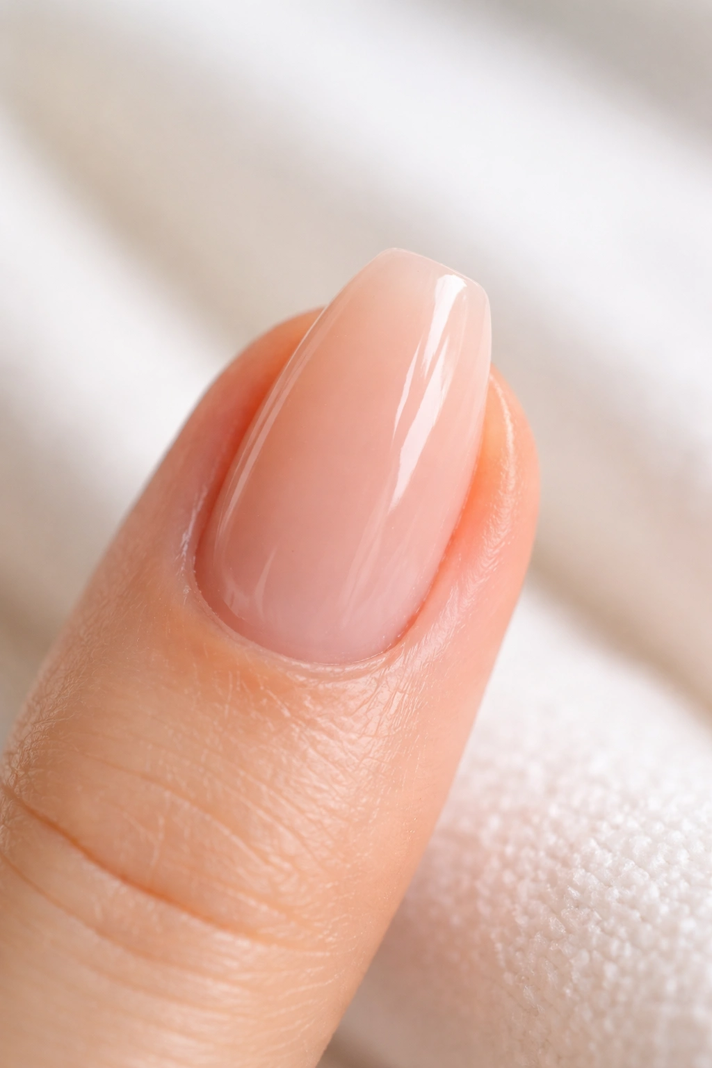 Close-up of a short ballerina nail with sheer peach builder base