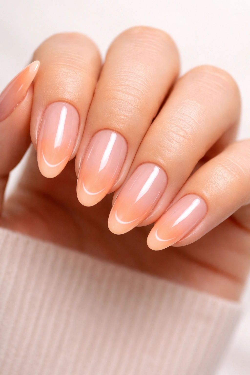 Close-up of peach-tipped French manicure on nude base with glossy glaze