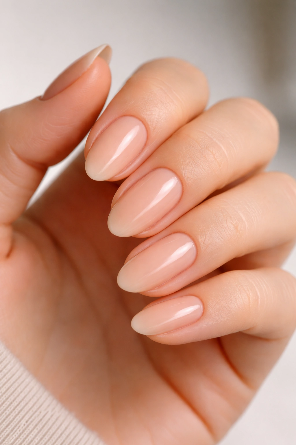 Close-up of barely there peach almond nails on a hand