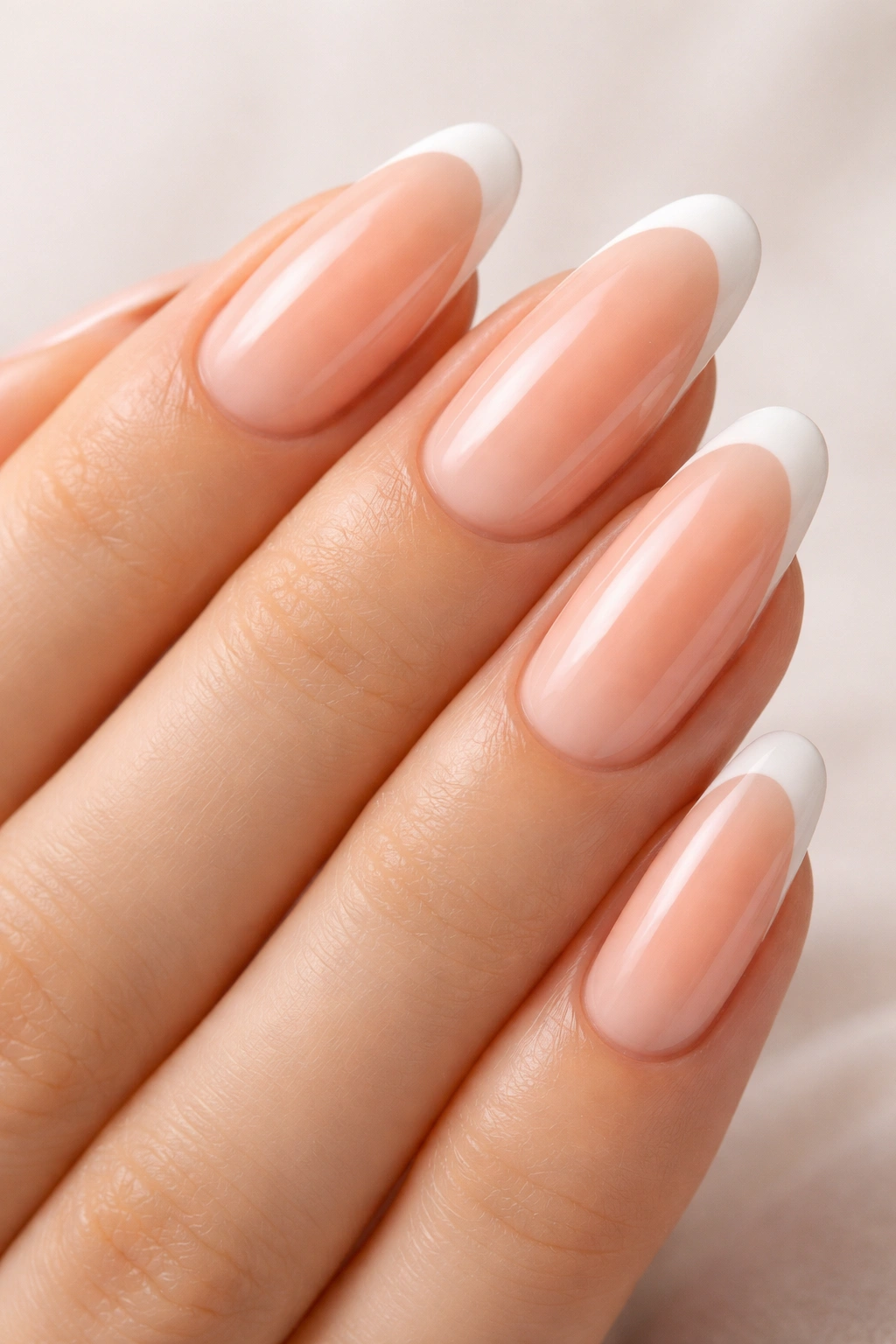 Close-up of long round nails with peach base and white French tips