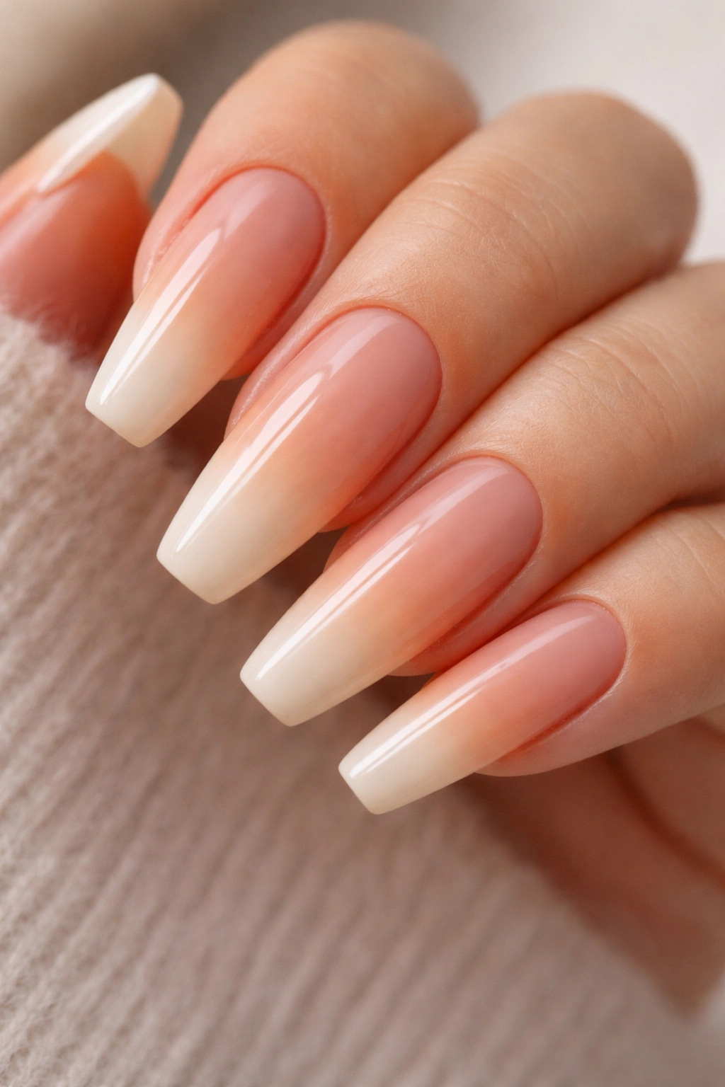 Close-up of peach nude to apricot ombre on tapered ballerina nails with a glossy finish