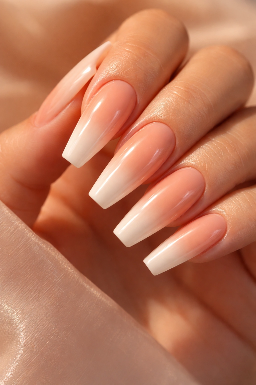 Close-up of peach-to-nude ombre nails on coffin shape with glossy finish