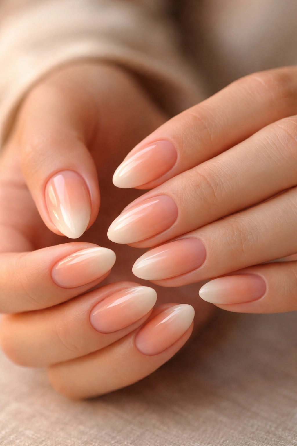 Close-up of short almond nails with peach ombre and warm glow