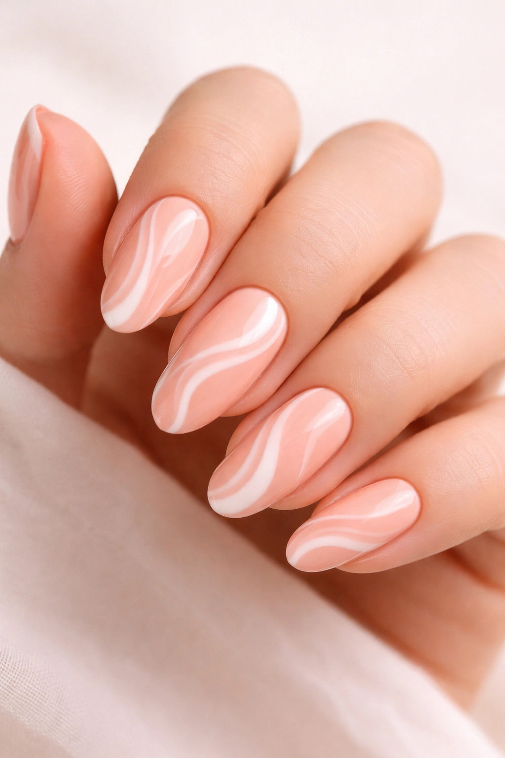 Close-up of nails with peach base and white swirl artwork on a neutral backdrop