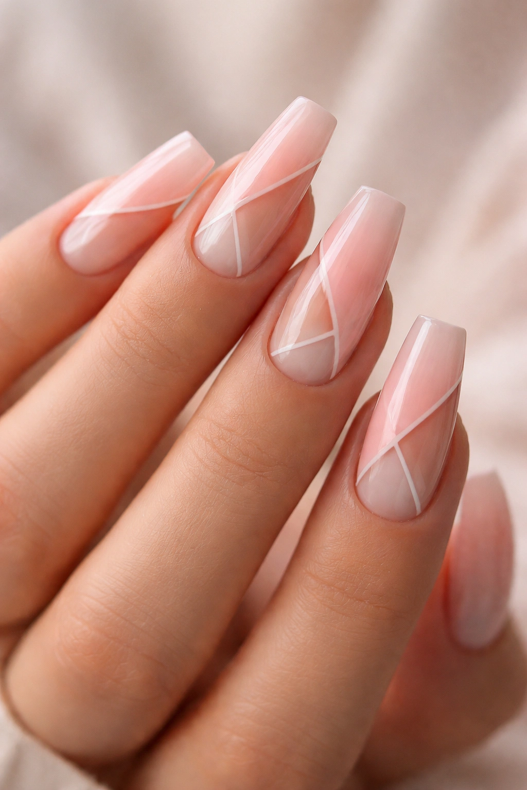 Close-up of peachy blush coffin nails with negative space geometric design