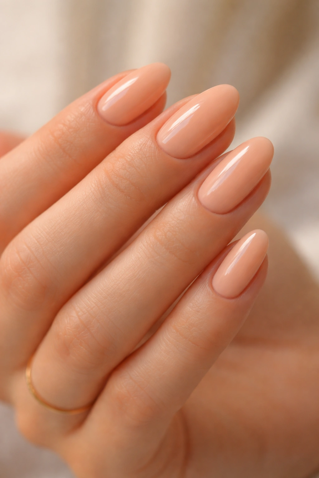 Close-up of peachy nude short almond nails with cream finish