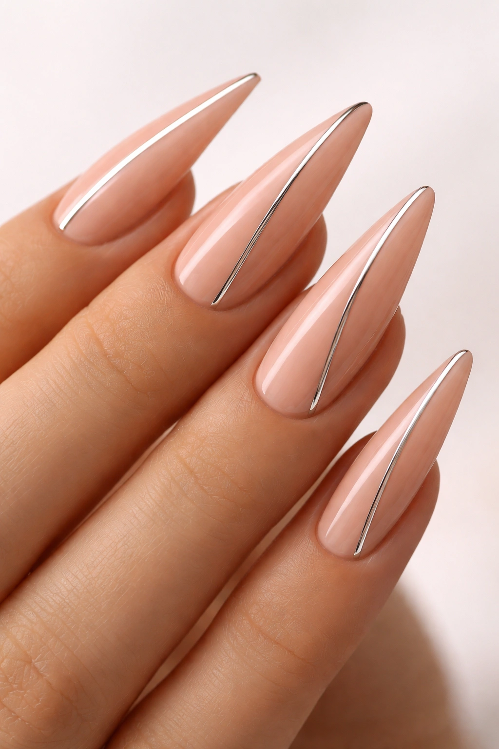 Close-up of peachy nude nails with thin chrome lines