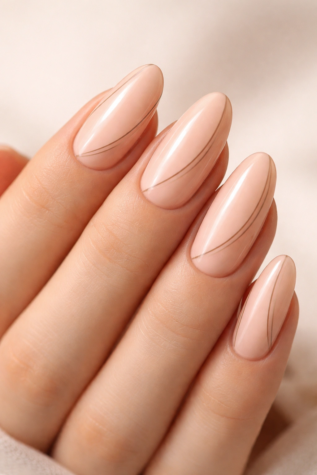 Close-up of oval nails with peachy-nude base and fine taupe lines.