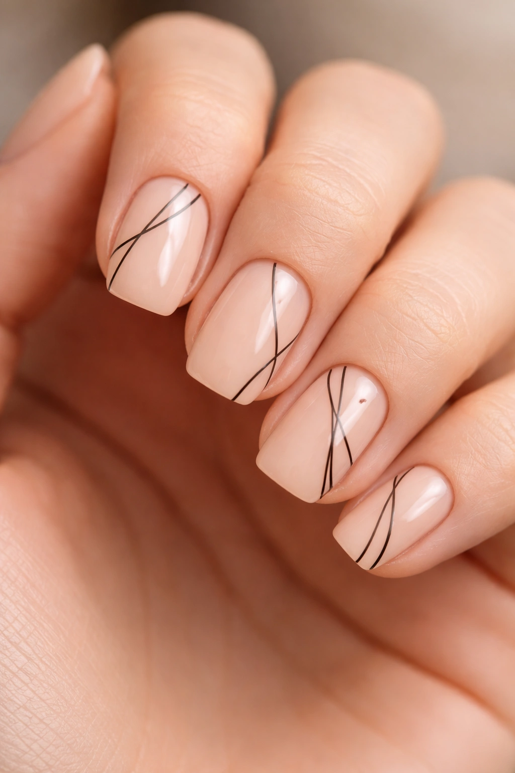 Close-up of peachy nude nails with skinny black line work on squoval nails