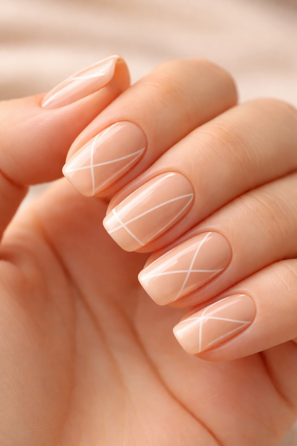 Close-up of short squoval nails showcasing peachy nude base with geometric negative-space outlines