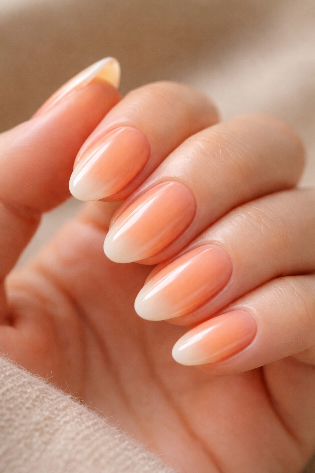 Close-up of peachy orange nails with milky white undershade on short almond nails