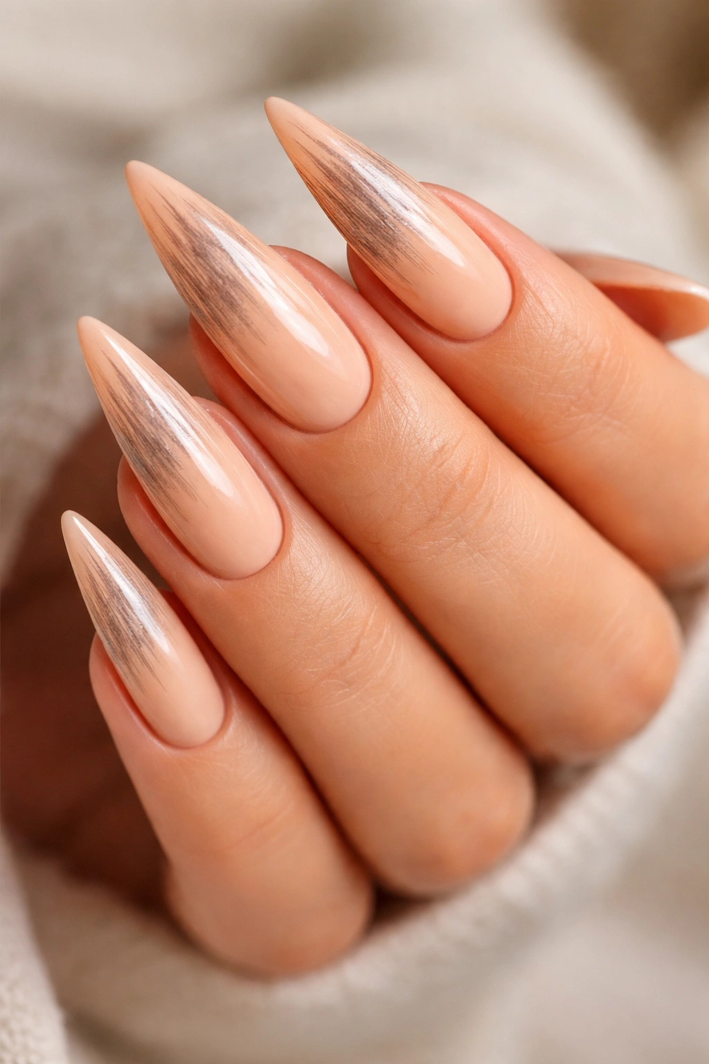 Close-up of peachy tan stiletto nails with dry brush texture