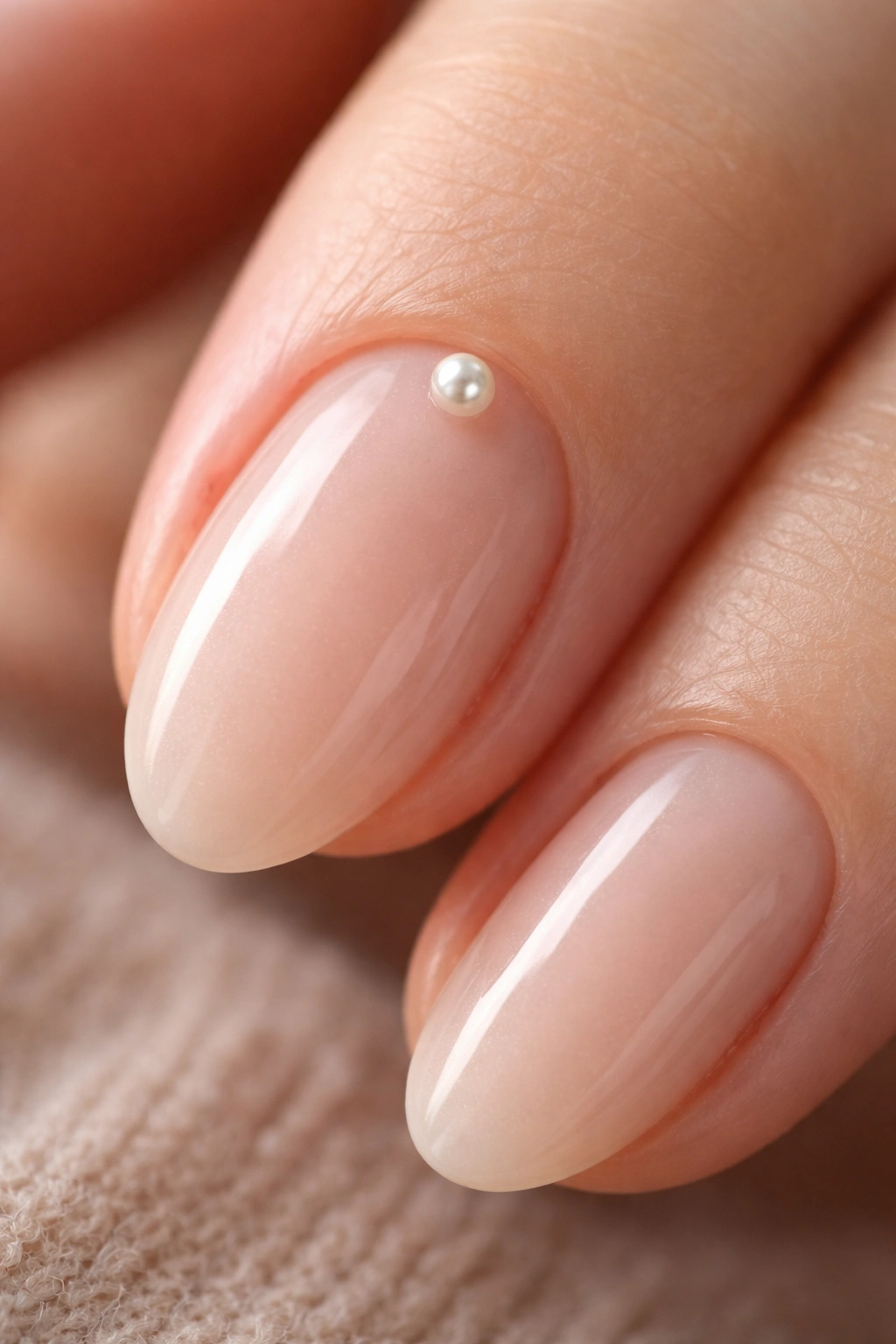 Close-up of a single almond nail with a tiny pearl accent near the cuticle