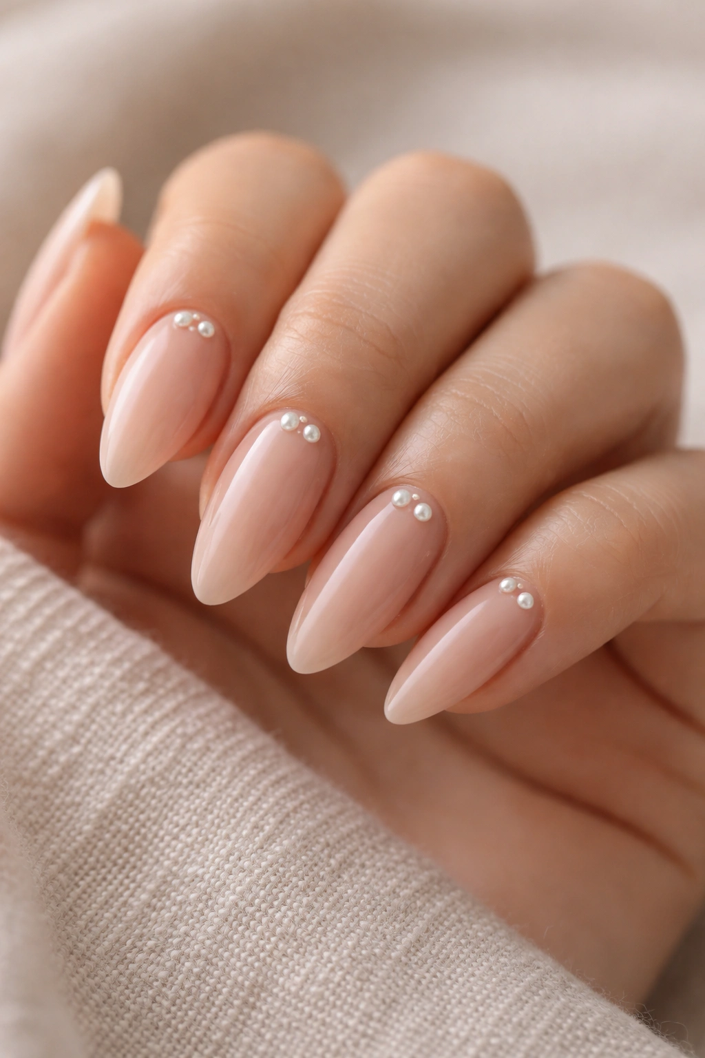 Close-up almond nails with pearl accents near base