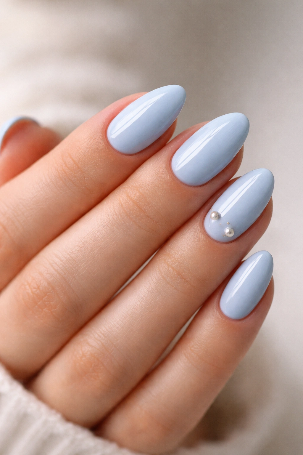 Close-up of baby blue nails with tiny pearl accents on short almond nails