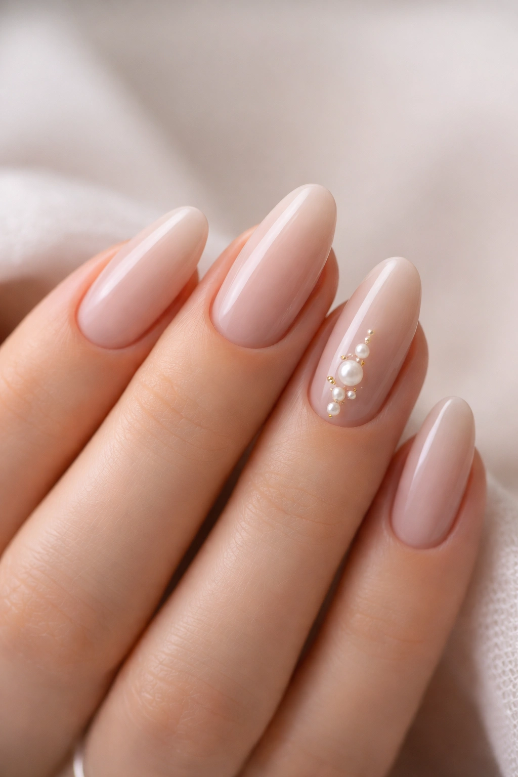 Close-up of nails with tiny pearl accents on a neutral base