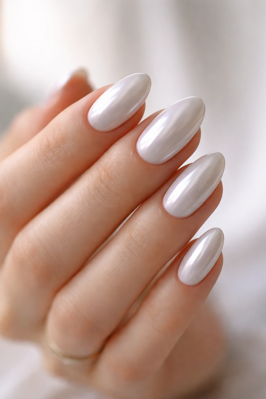 White pearl chrome almond nails close-up on hand