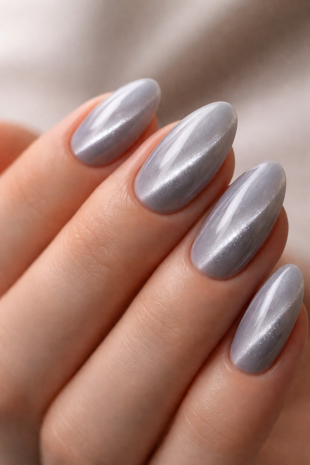 Close-up of short almond nails in pearl gray with silver cat eye shimmer